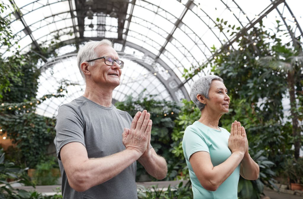 Senior couple enjoying a yoga session indoors, promoting harmony and healthy lifestyle.